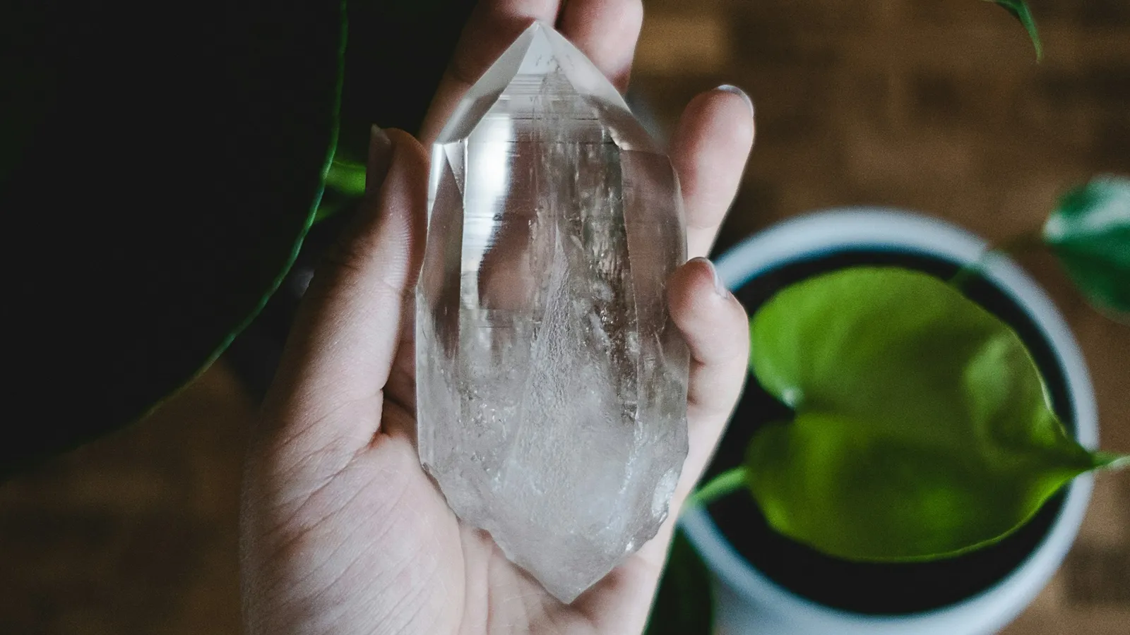 A hand holding a clear crystal