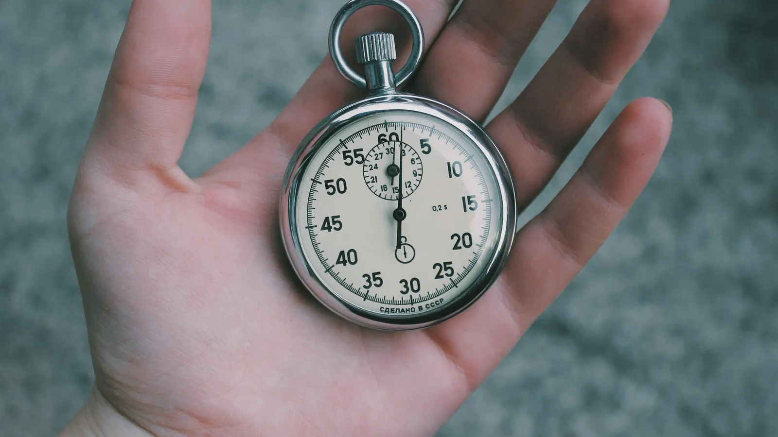 A hand holding a mechanical stopwatch