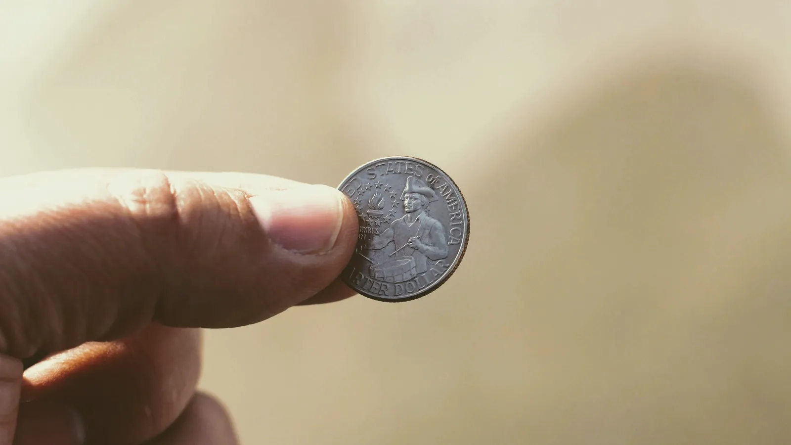 A hand holding up a coin
