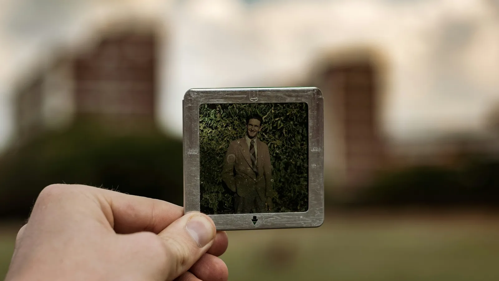 A hand holding up a small photographic slide