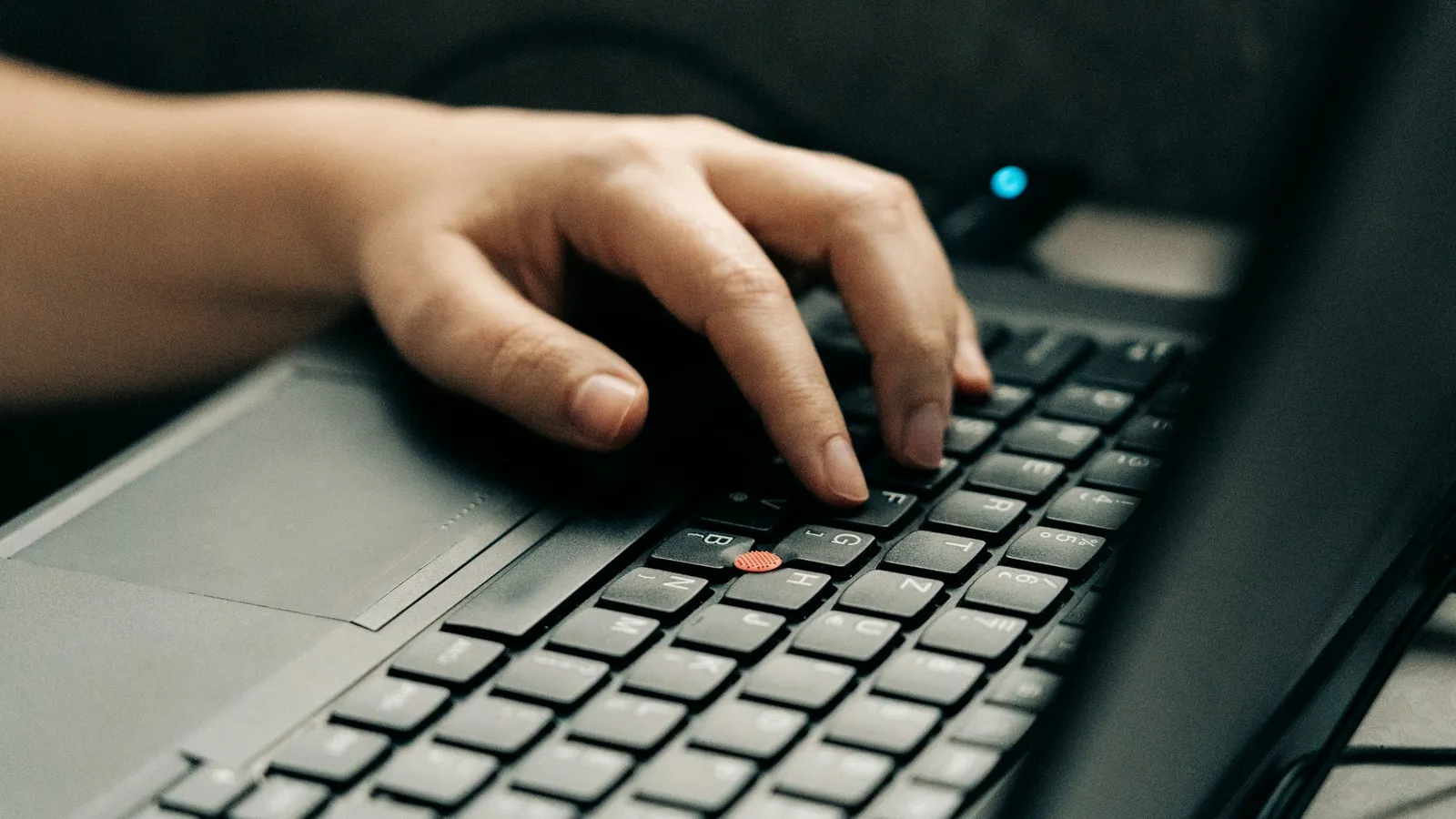A hand on a computer mouse beside a laptop