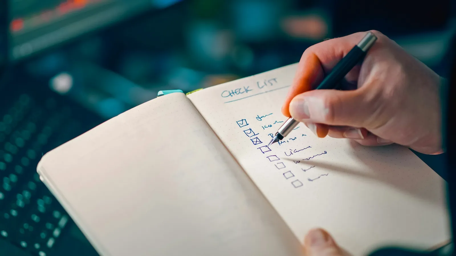 A hand ticking items off a list in a notebook