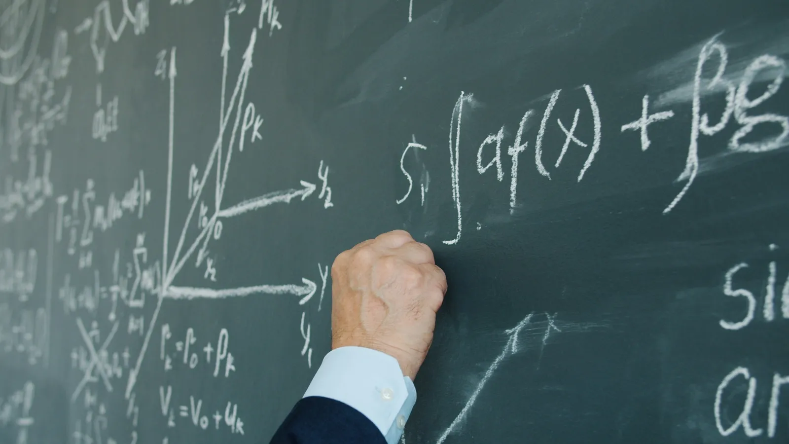 A hand writing an integral on a chalkboard