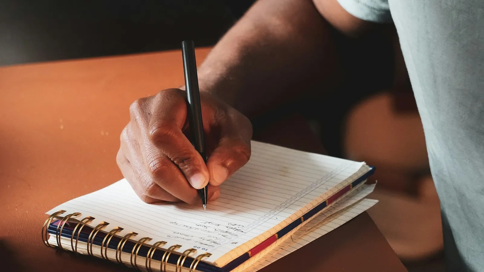 A hand writing in a spiral notebook