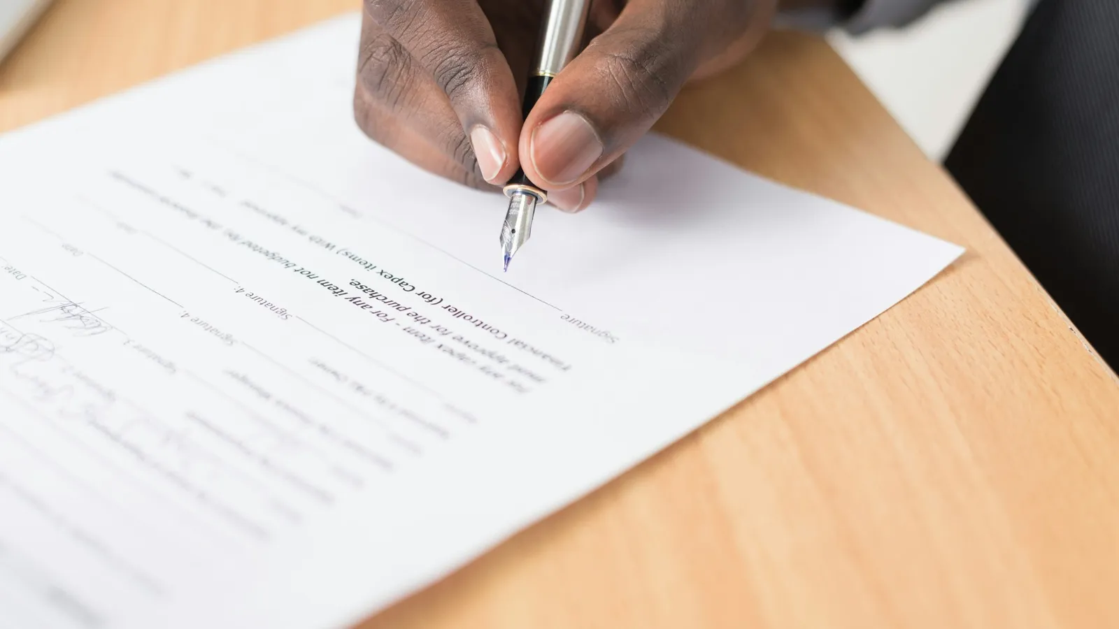 A hand writing on a sheet of paper with a pen