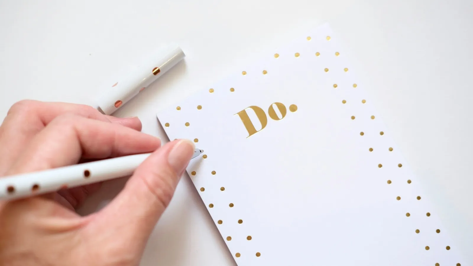A hand writing on a to-do list with a white pen