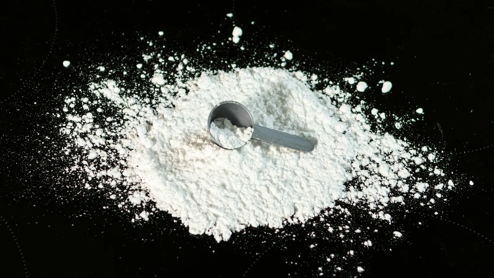 A heap of white powder with a scoop on black