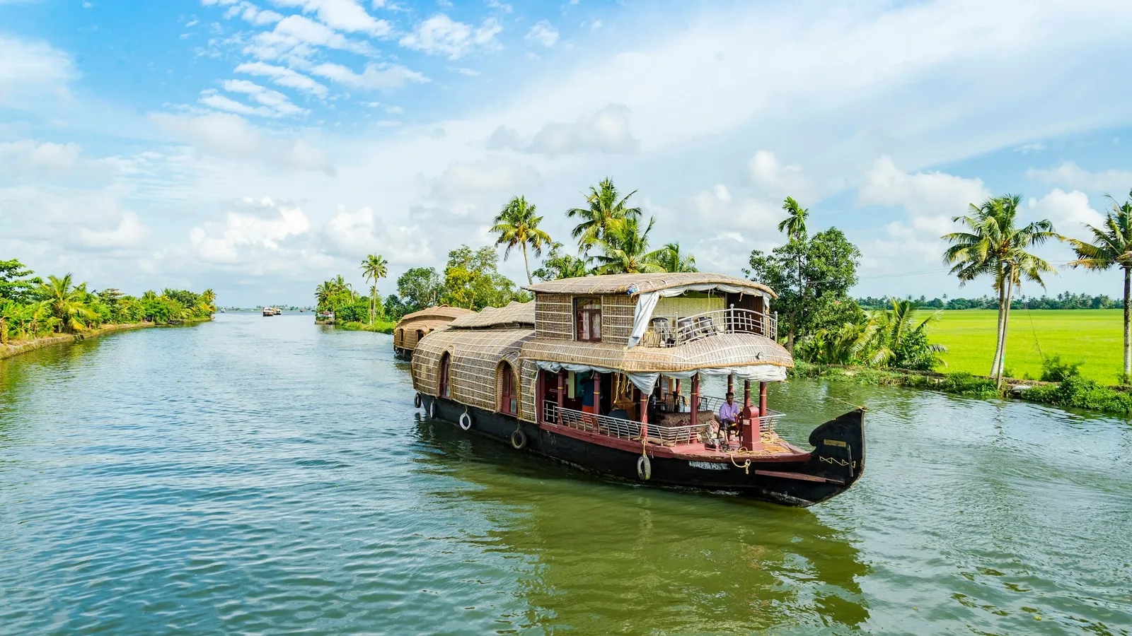 A houseboat on a wide Kerala backwater under a blue sky