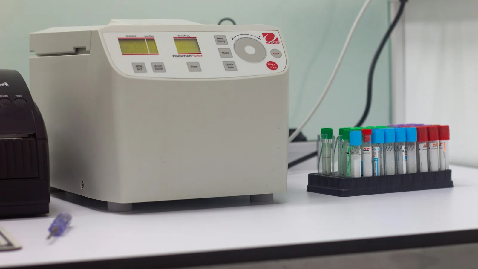 A lab centrifuge beside a rack of sample tubes