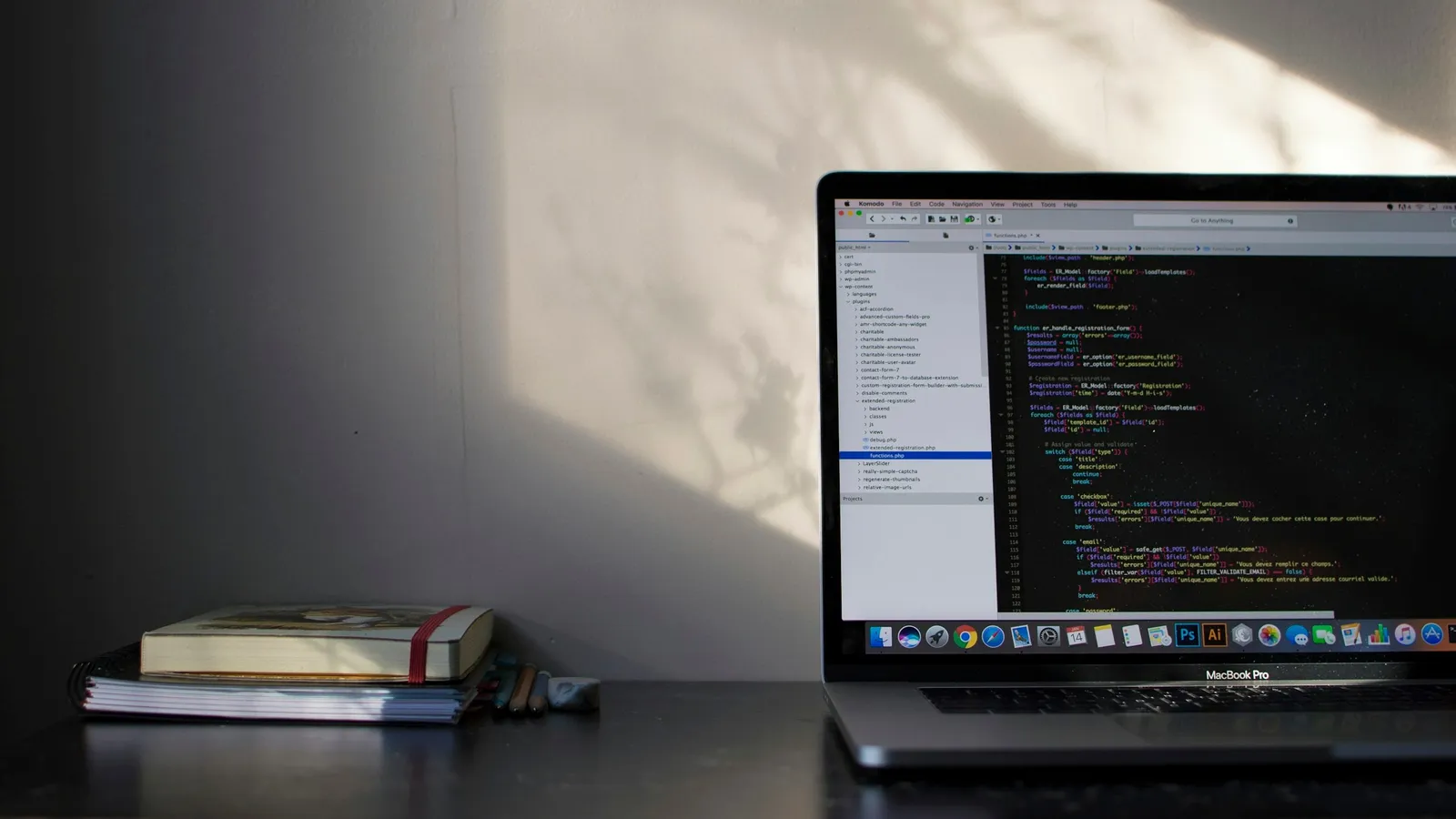 A laptop showing code beside a stack of books