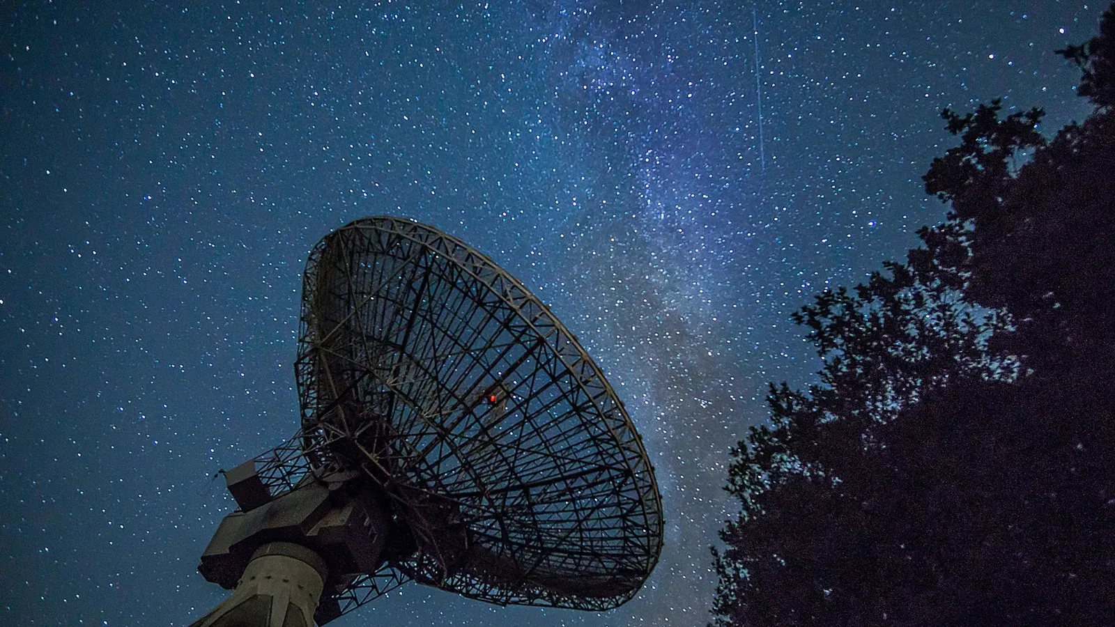 A large dish antenna under a starry night sky