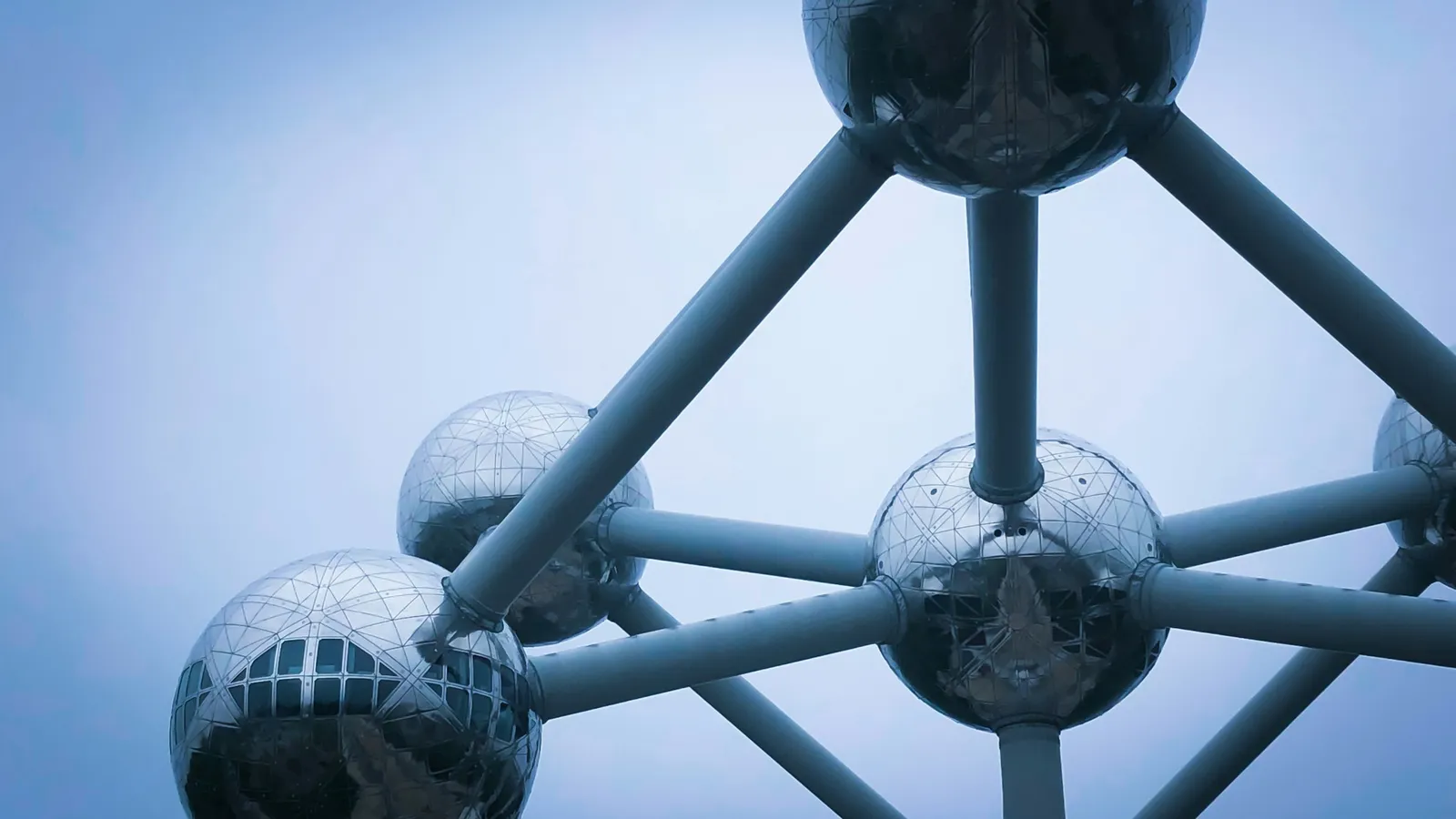 A large steel model of atoms joined by tubes against a blue sky