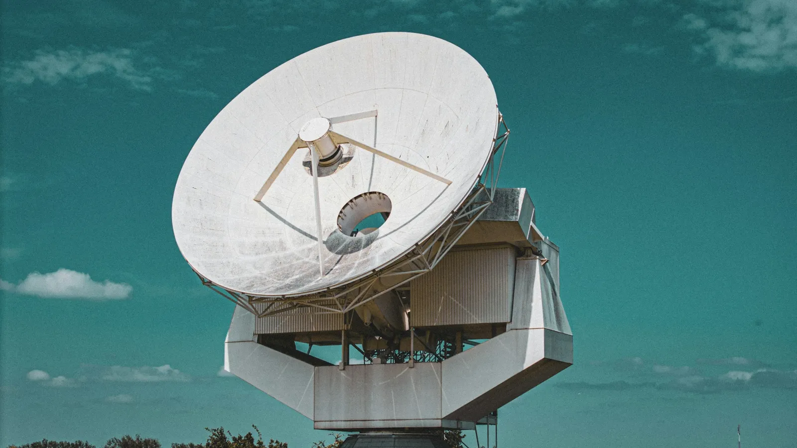 A large white dish antenna against a blue sky