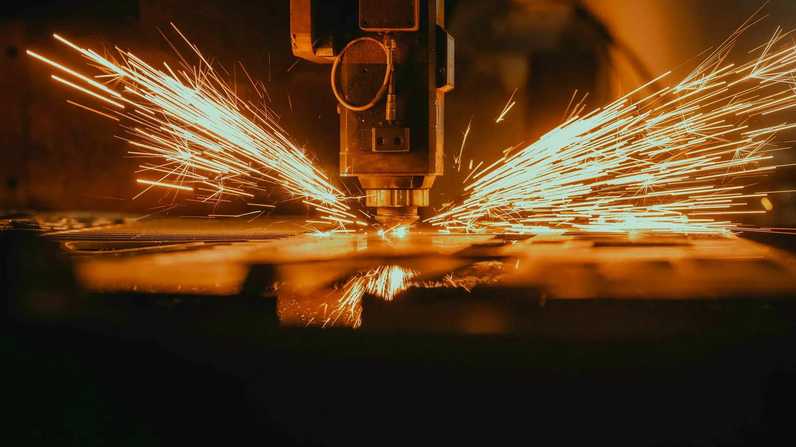 A laser cutter throwing sparks as it cuts metal