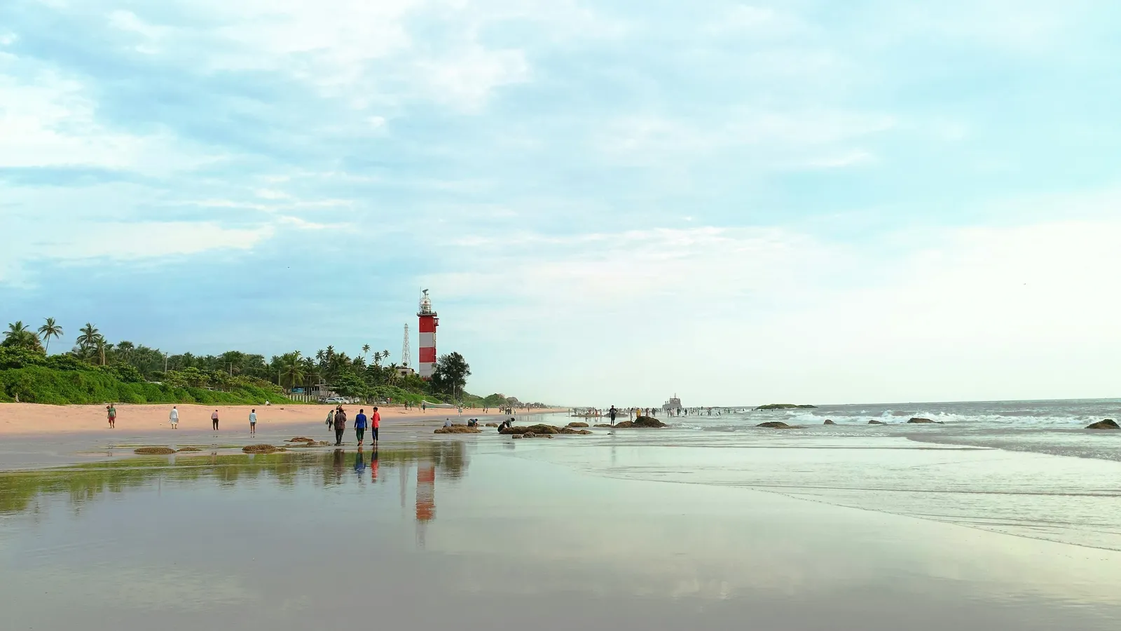 A lighthouse beside a wide beach on the Karnataka coast