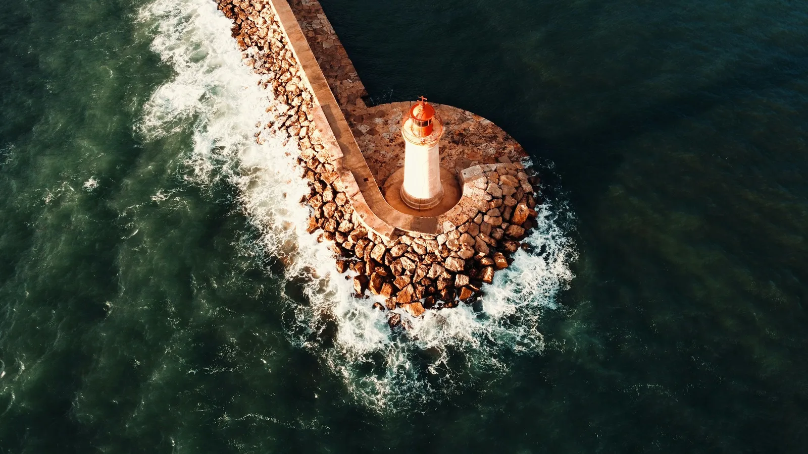 A lighthouse on a rocky point with waves breaking around it
