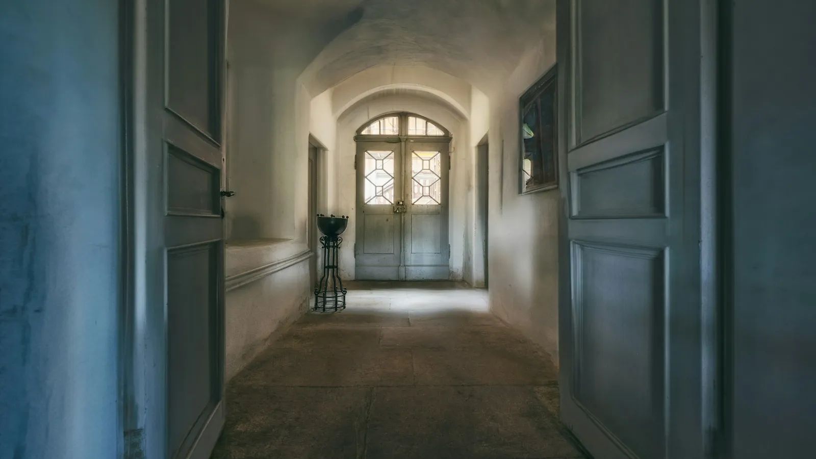 A long hallway with open doors leading to a bright window