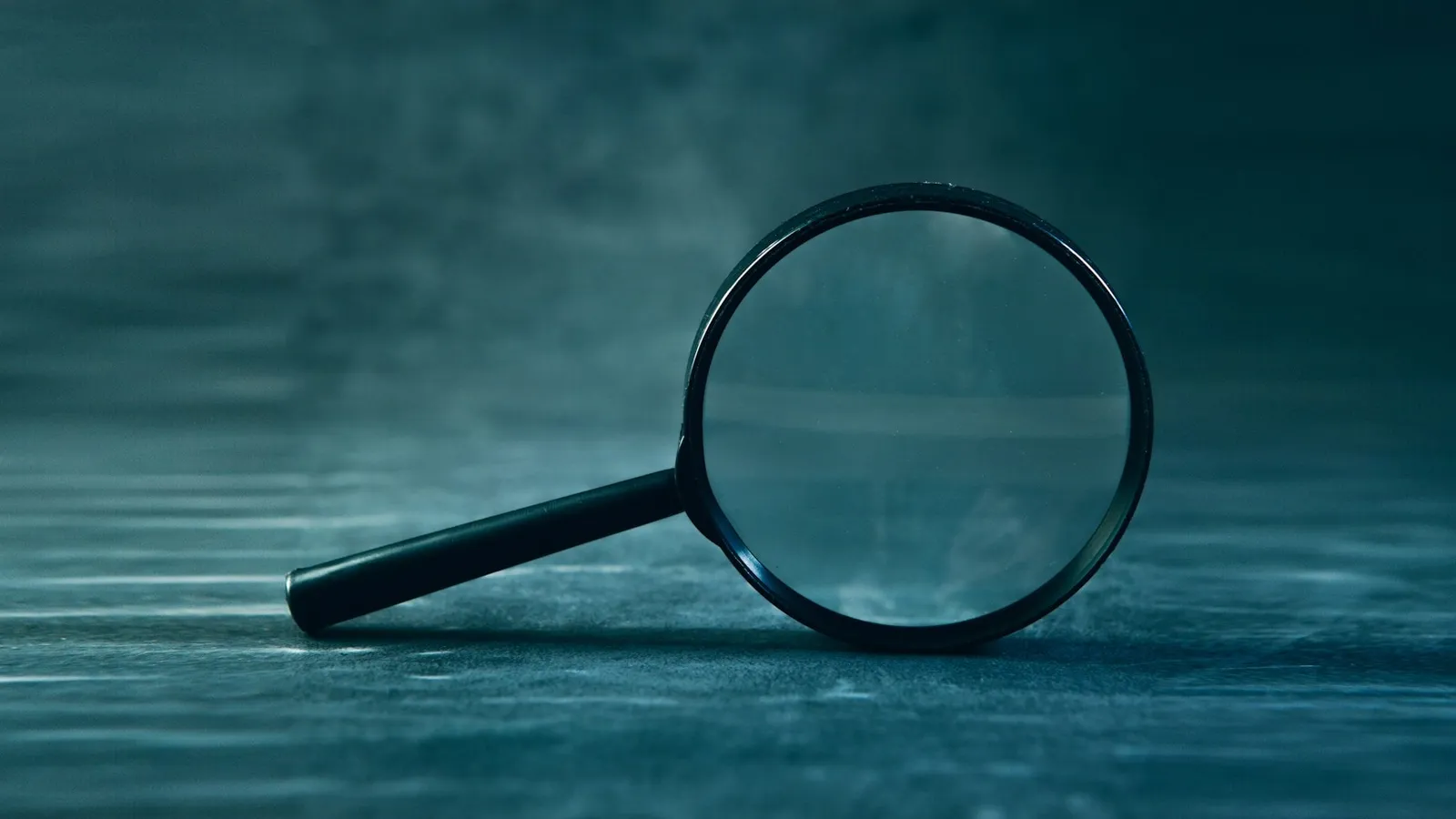 A magnifying glass lying on a blue surface
