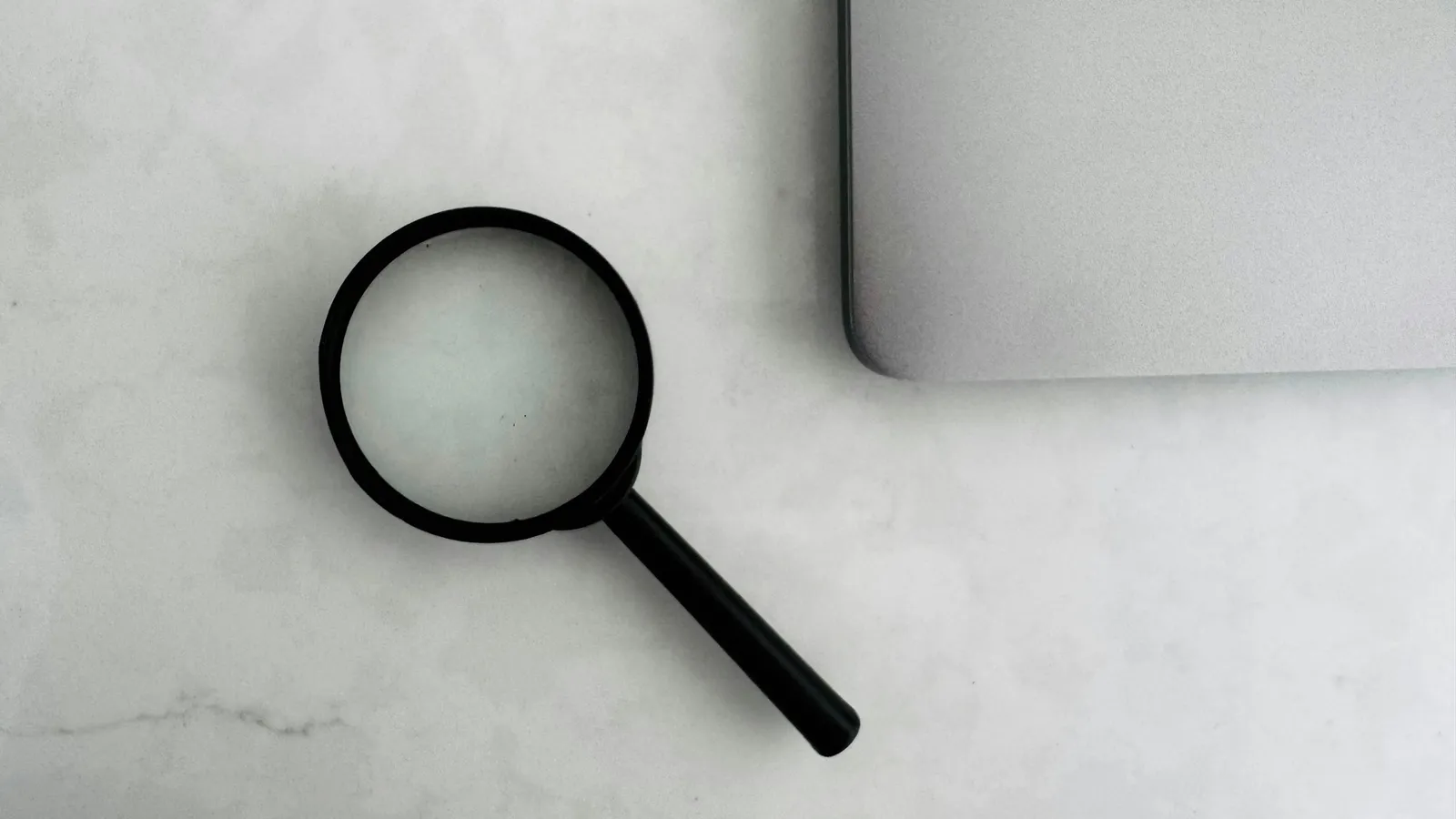 A magnifying glass on a pale desk