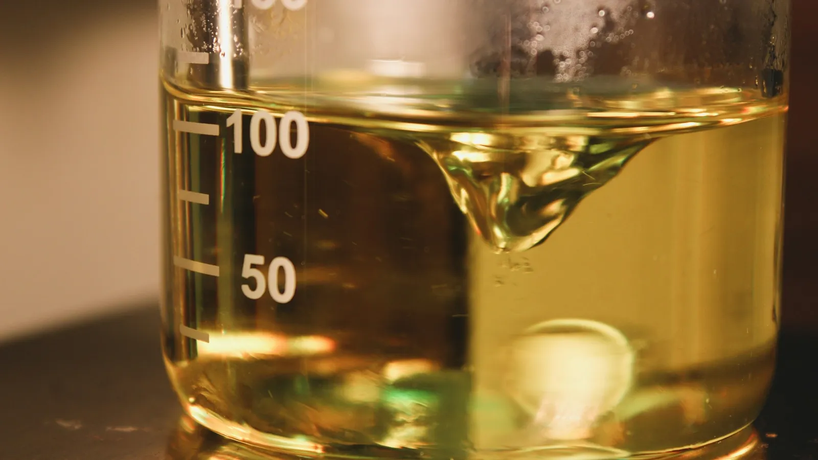 A measuring beaker holding yellow liquid with a scale on its side