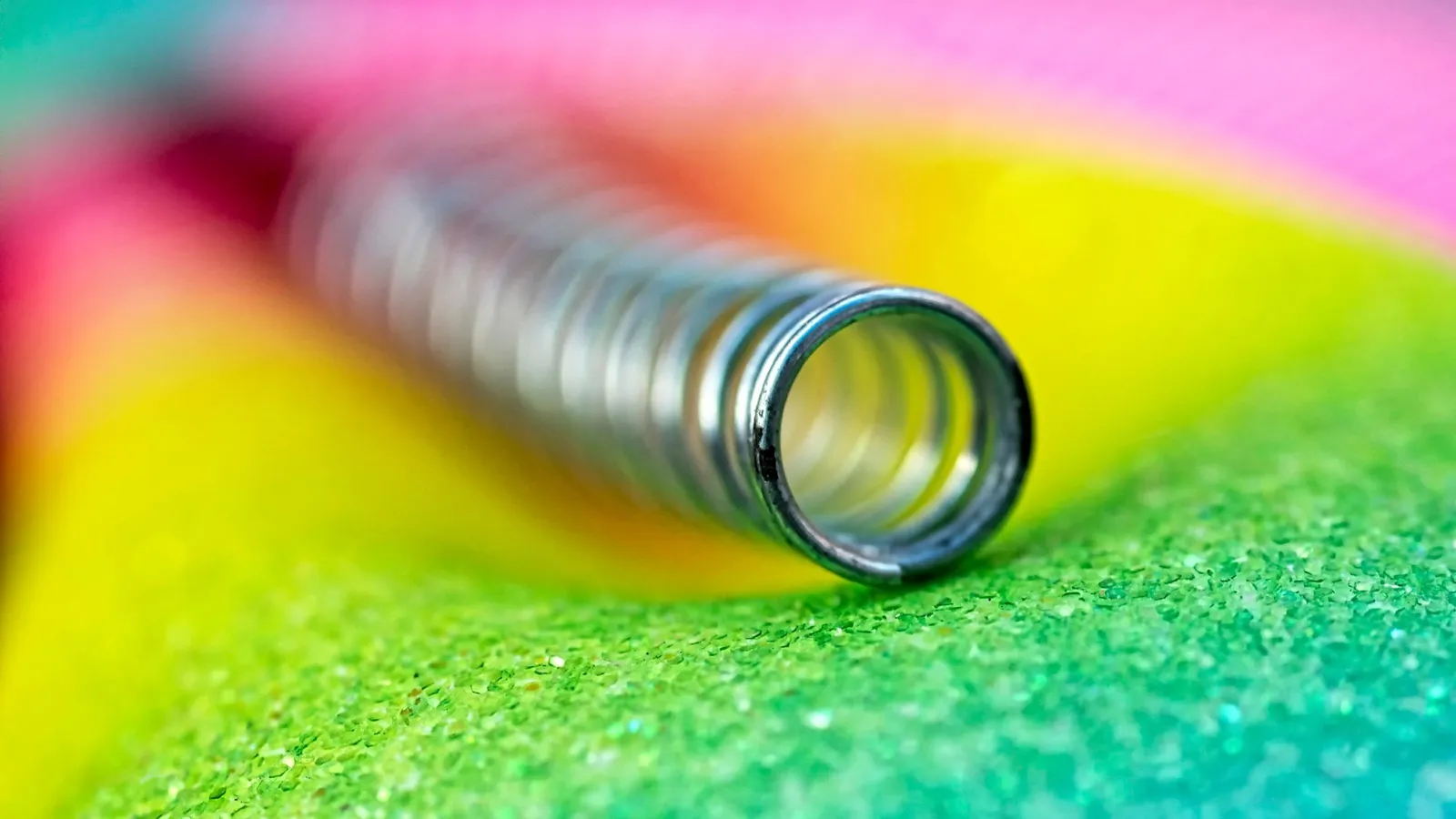 A metal spring lying on a colourful surface