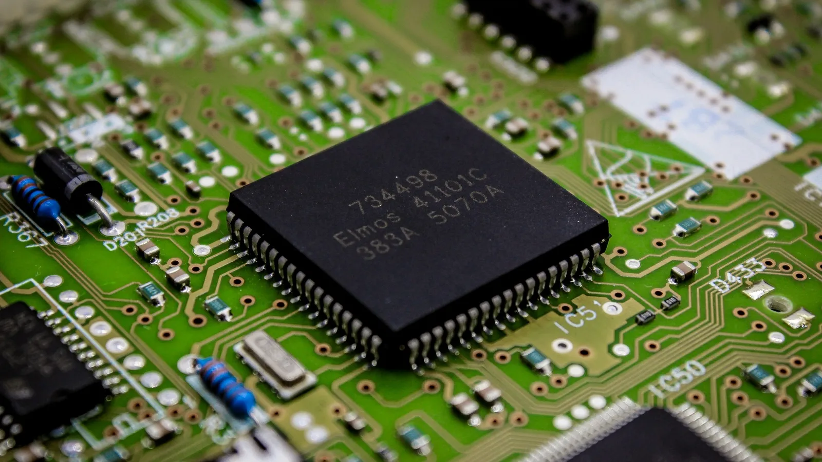 A microchip soldered onto a green circuit board