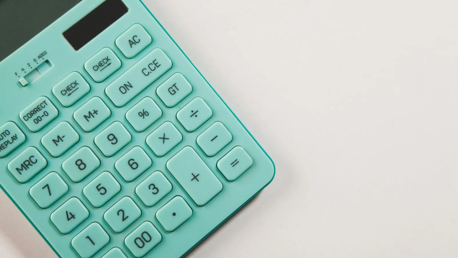 A mint green calculator on a white desk