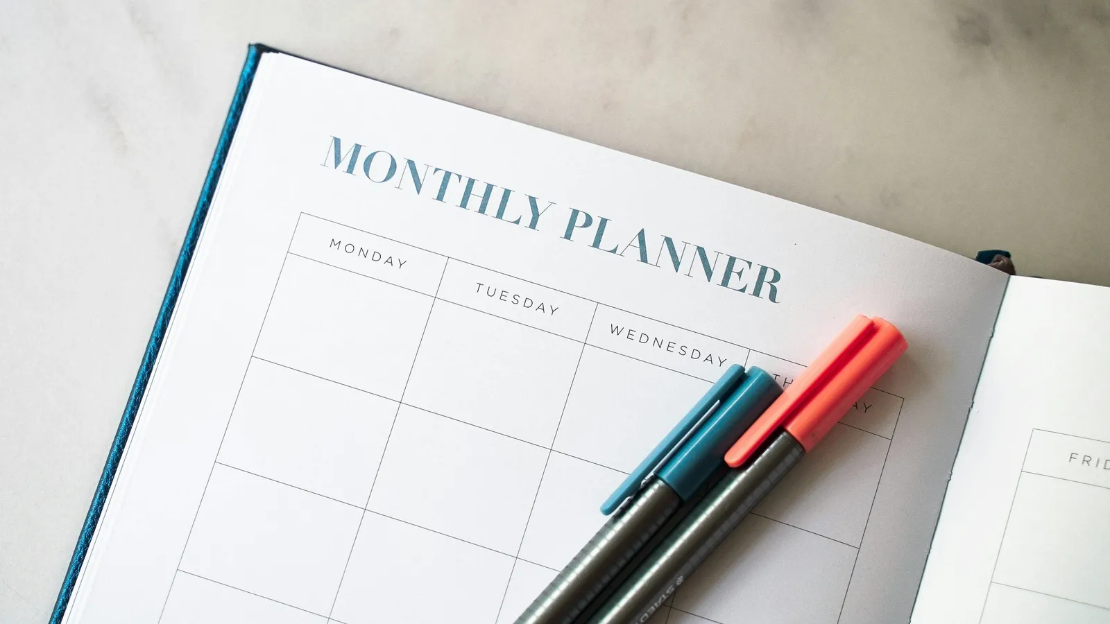 A monthly planner with two pens lying on it