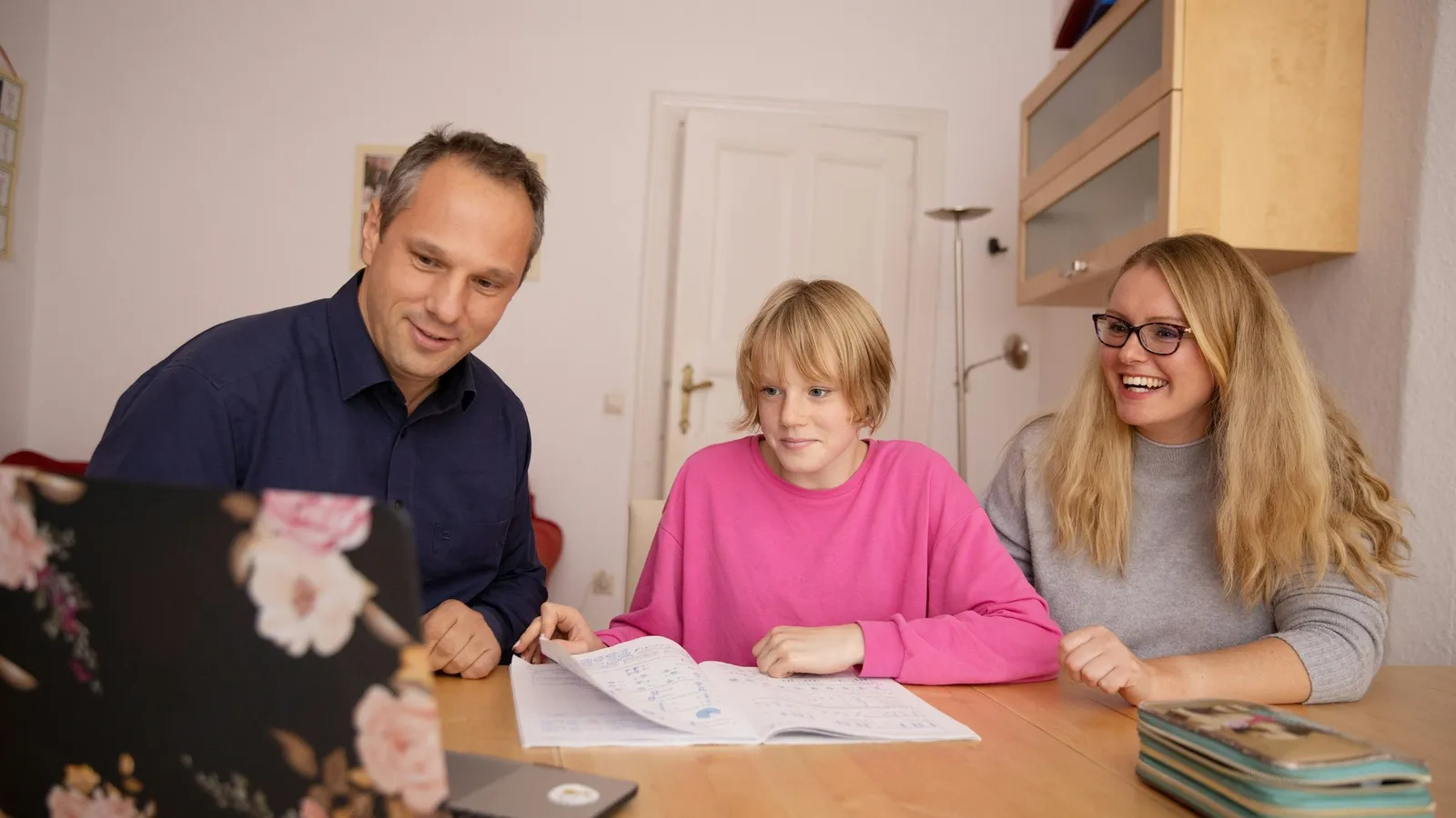A mother sitting beside her daughter as she does schoolwork