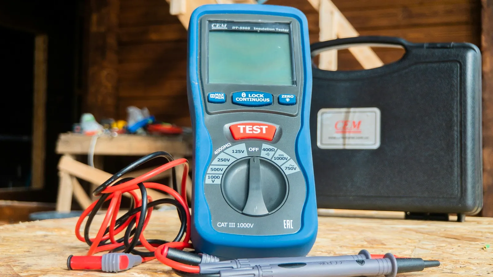 A multimeter and test leads on a wooden bench