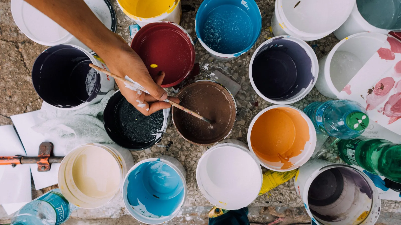A painter mixing colours from rows of paint pots