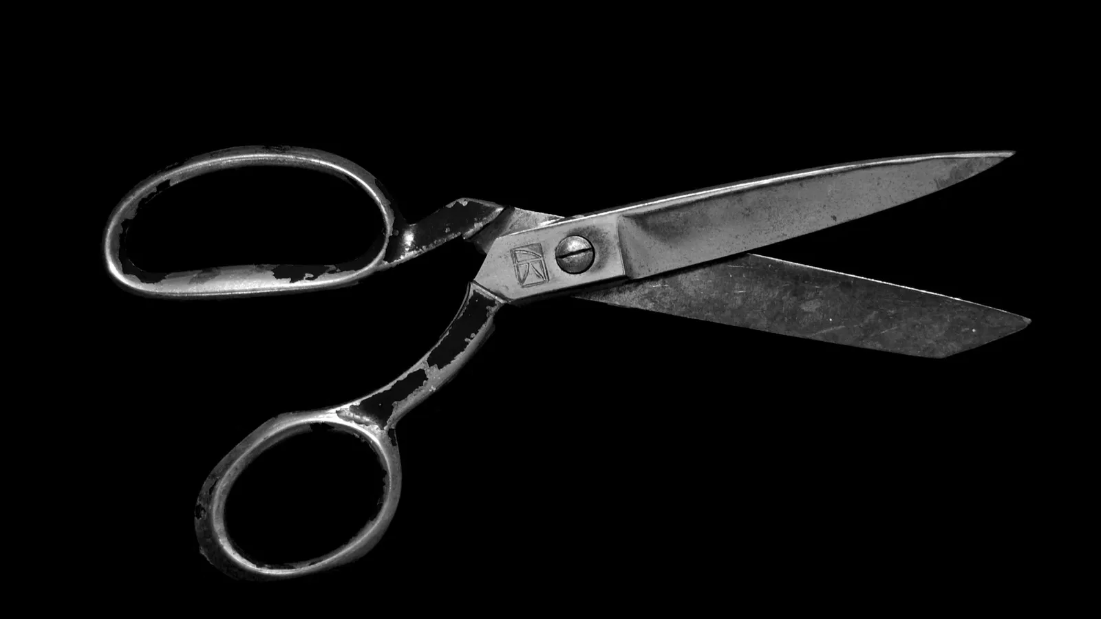 A pair of open scissors on a black background