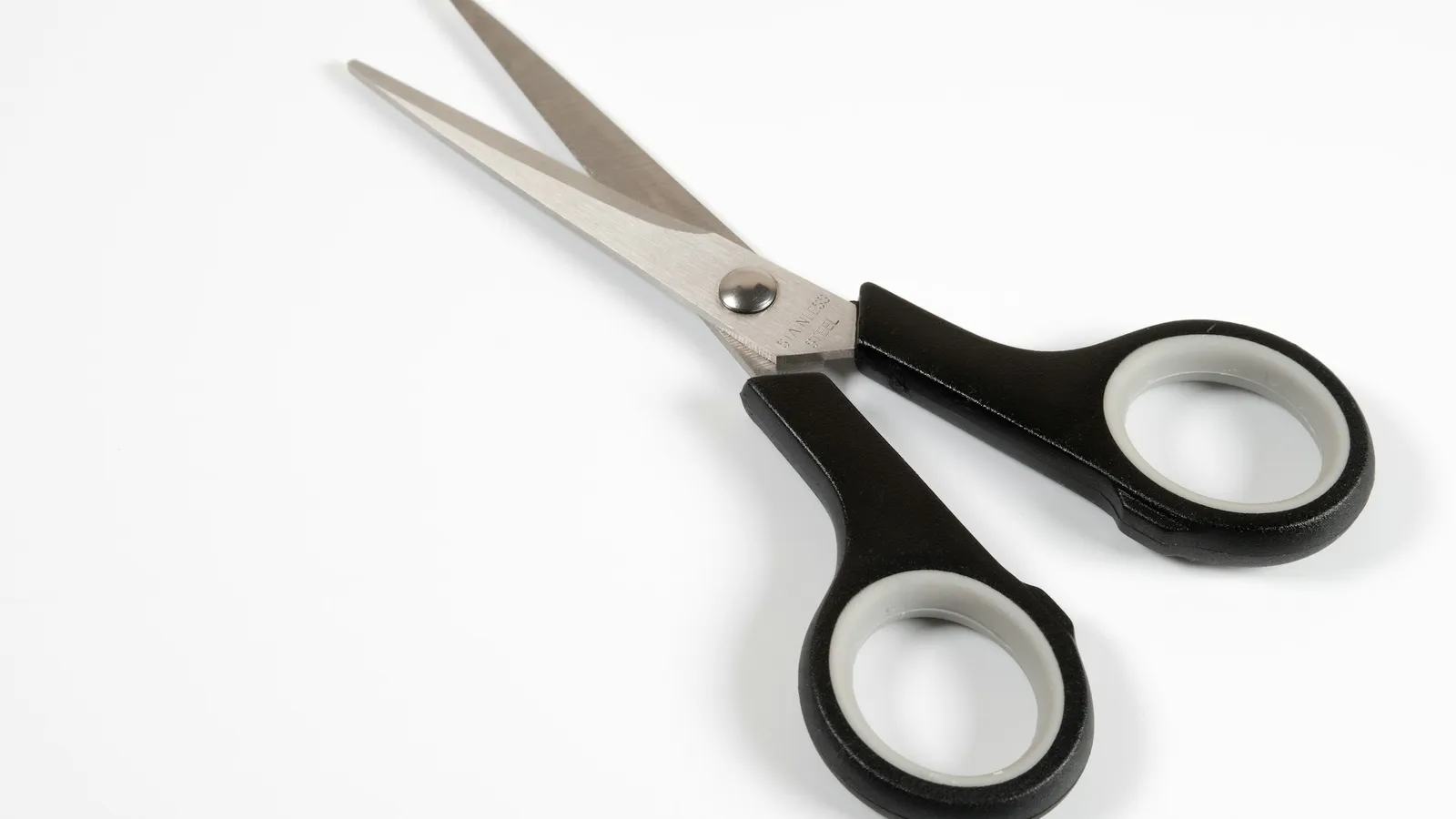 A pair of open scissors with black handles on white