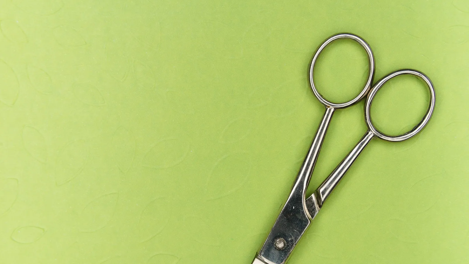A pair of scissors on a green background