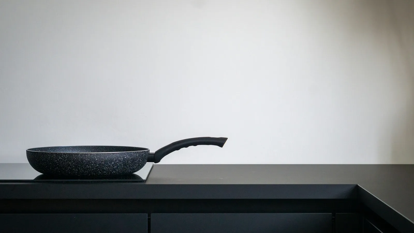 A pan resting on a flat black induction cooktop