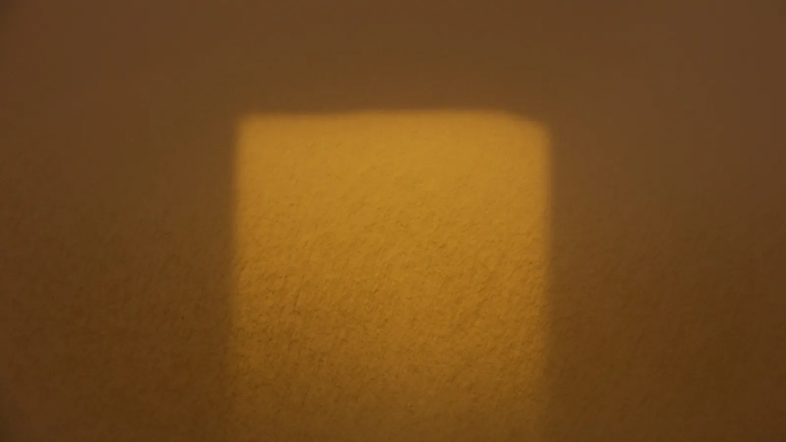 A patch of sunlight cast on a dim wall