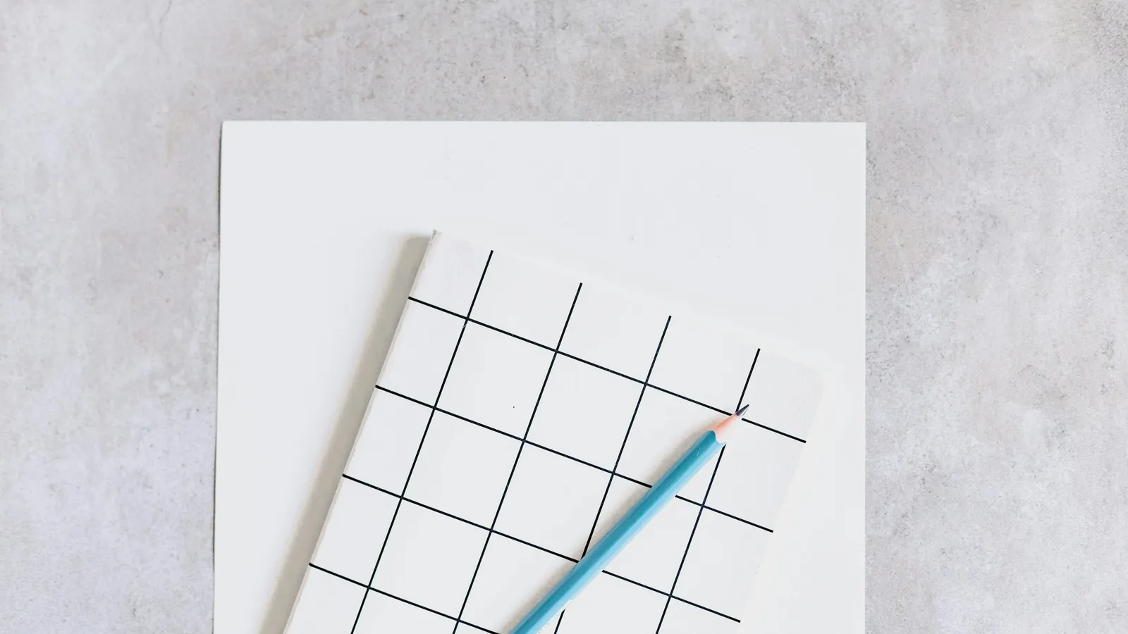 A pen resting on a sheet of grid paper on a grey surface