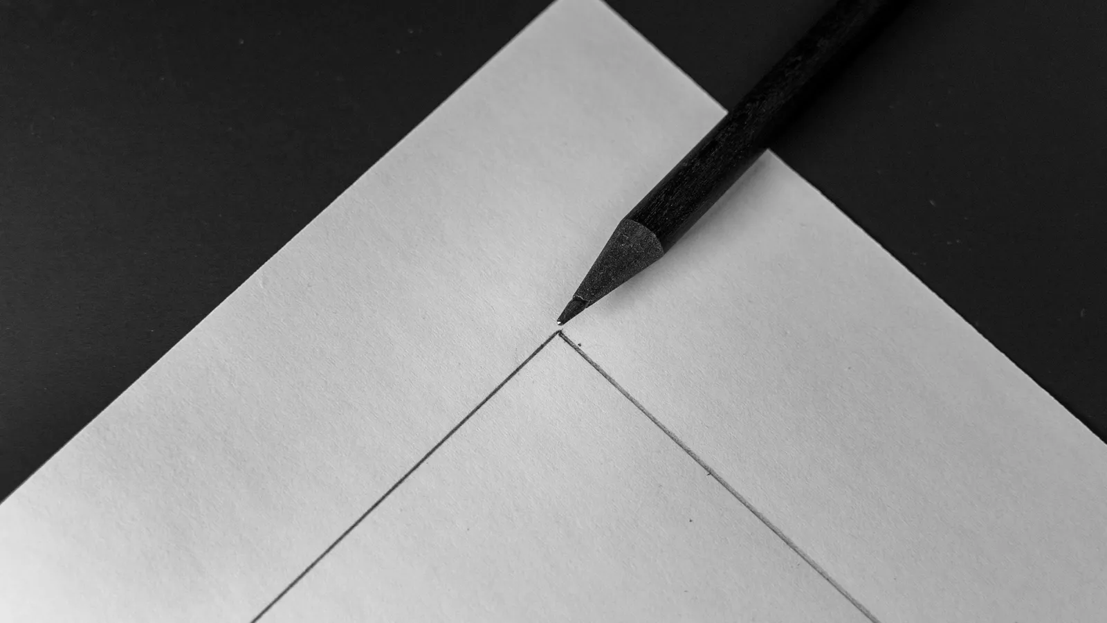 A pencil resting on folded white paper