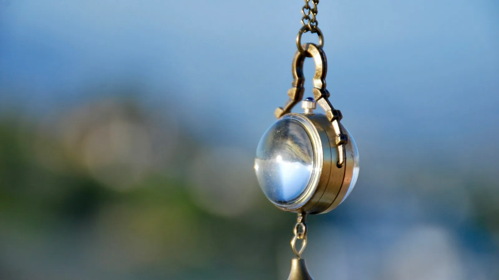 A pendant swinging on a chain against blue sky