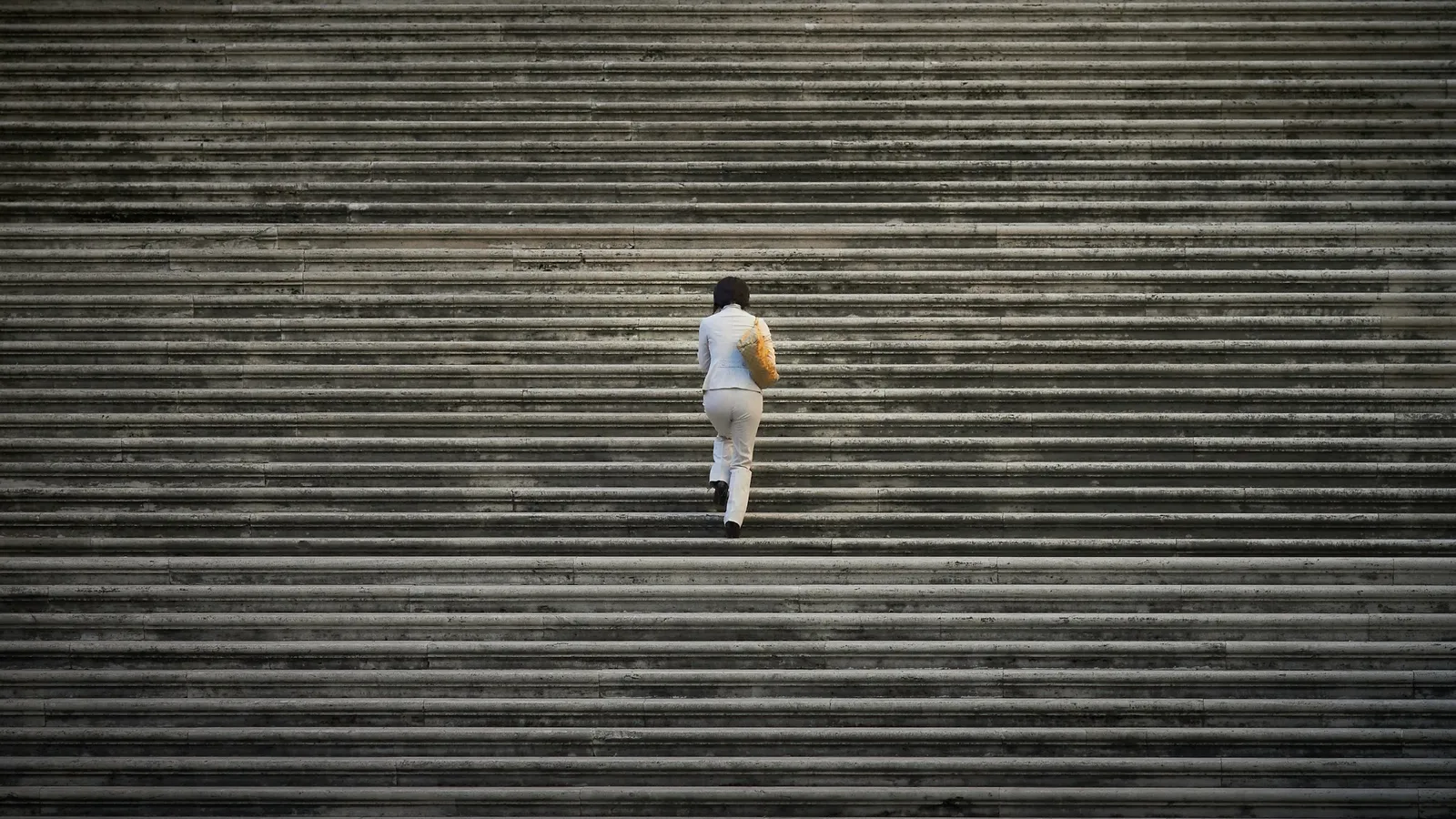 A person climbing a wide stone staircase