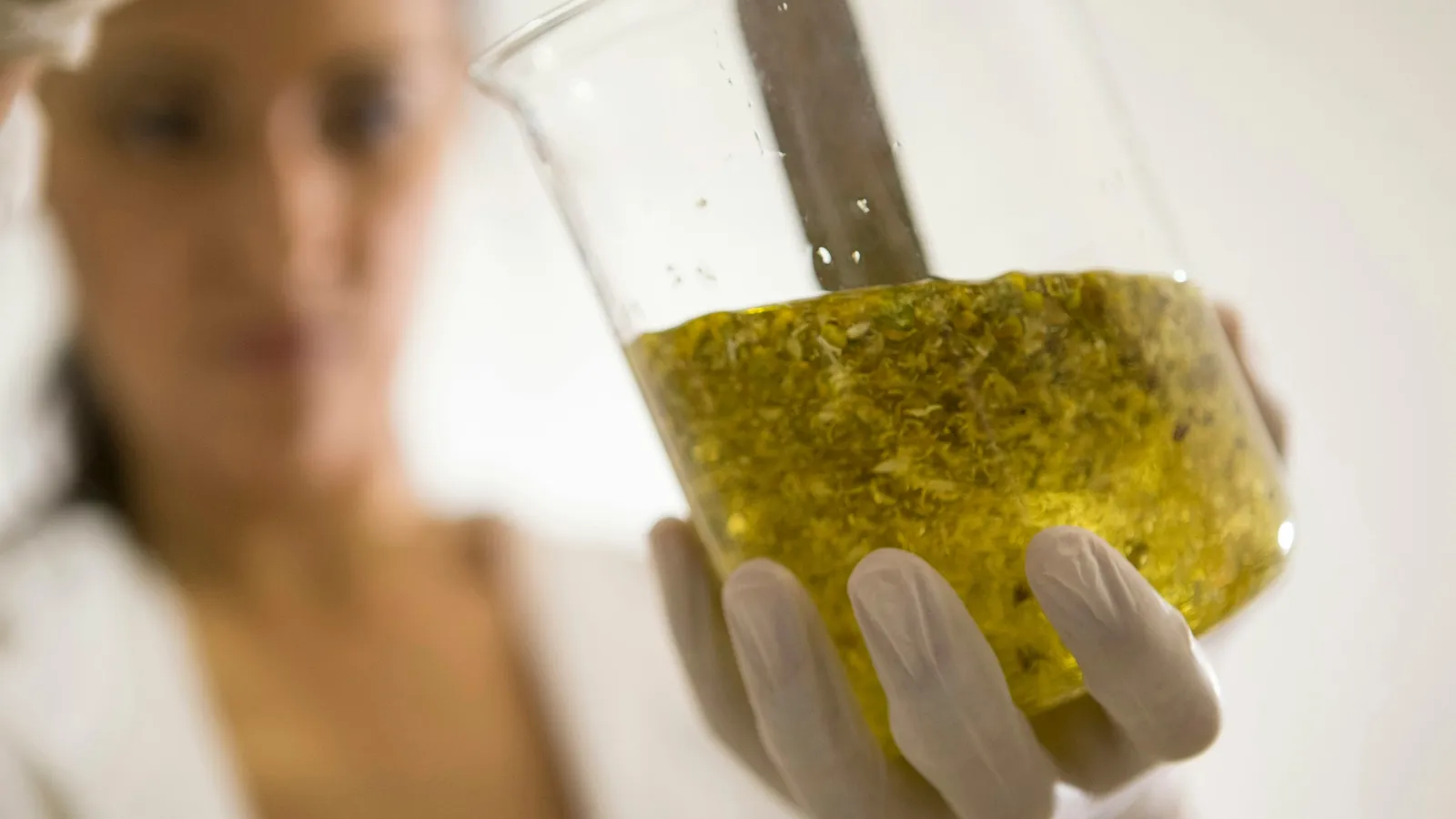 A person holding a flask of yellow liquid