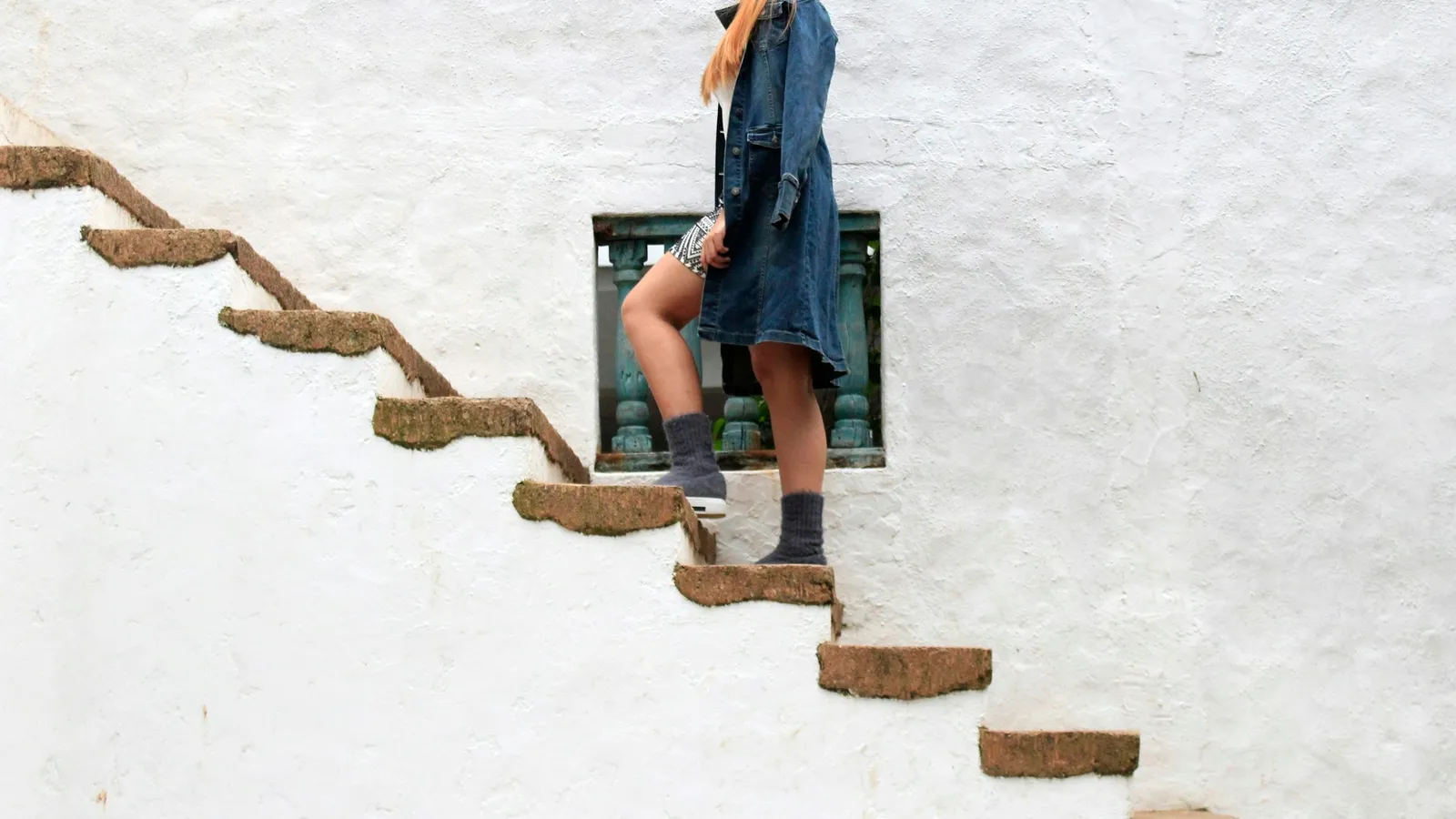 A person stepping up a staircase of floating wooden steps