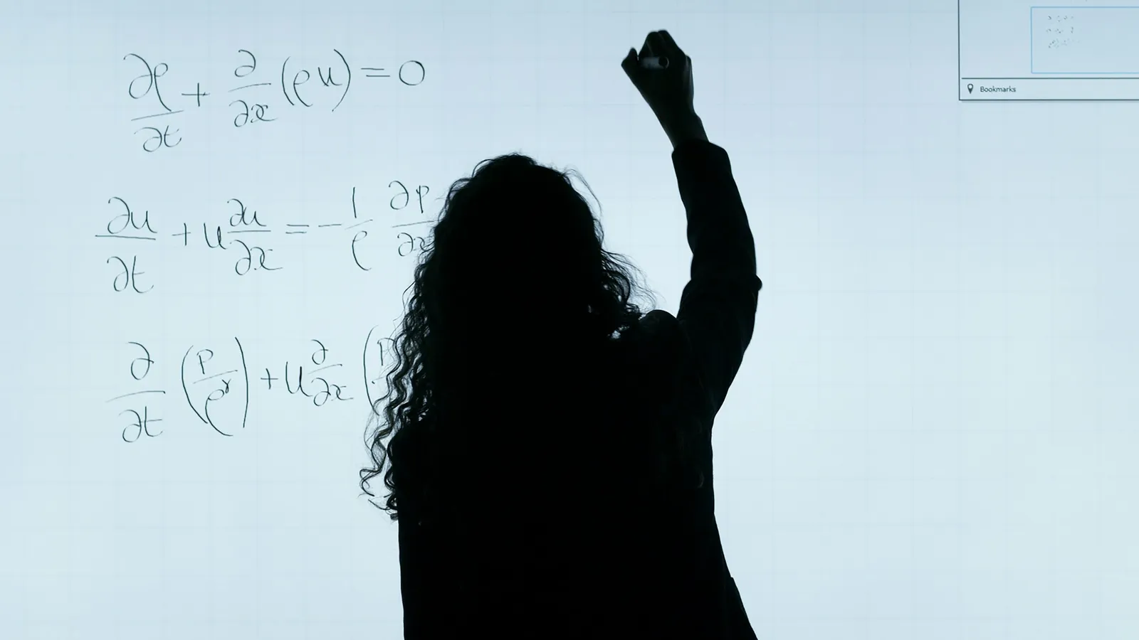 A person writing maths on a whiteboard, seen in silhouette