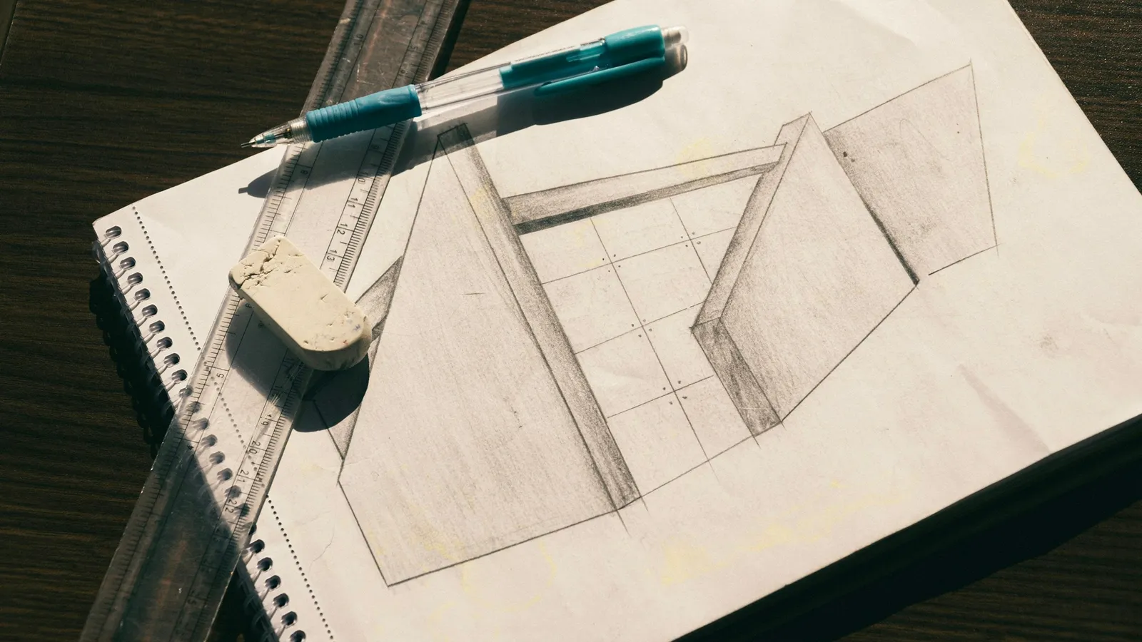 A perspective sketch of a building drawn on paper beside a pen