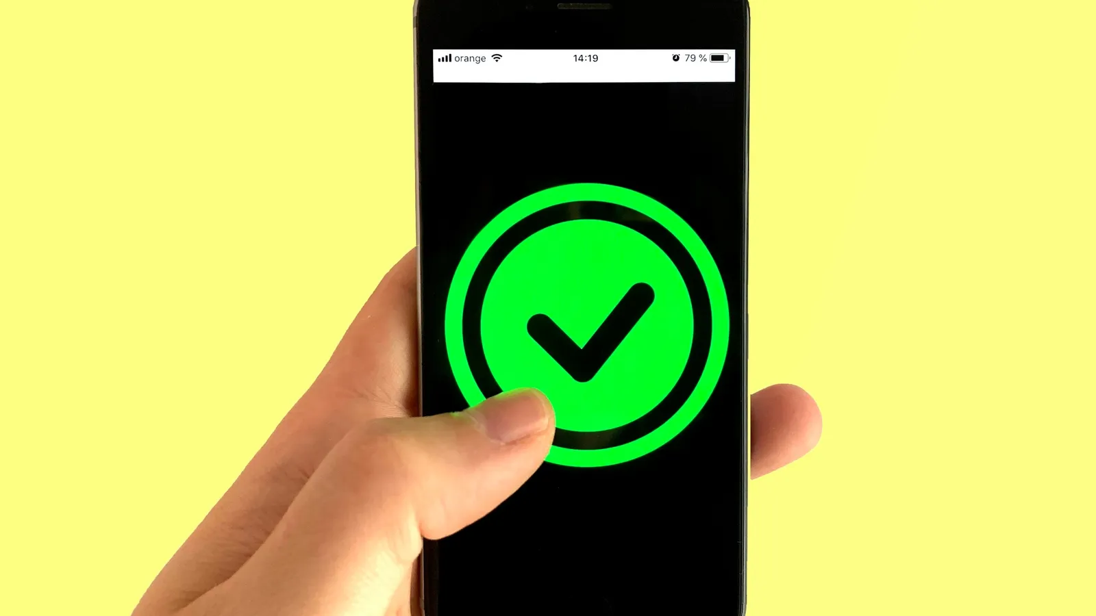 A phone screen showing a green tick against a yellow background