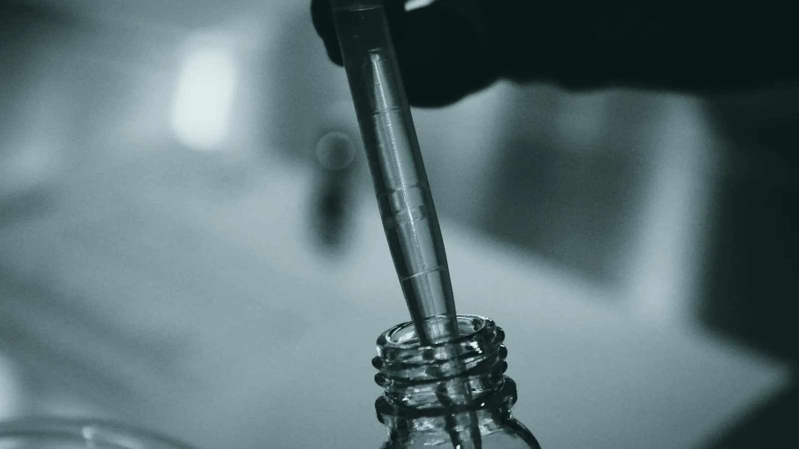 A pipette dripping into a glass vial