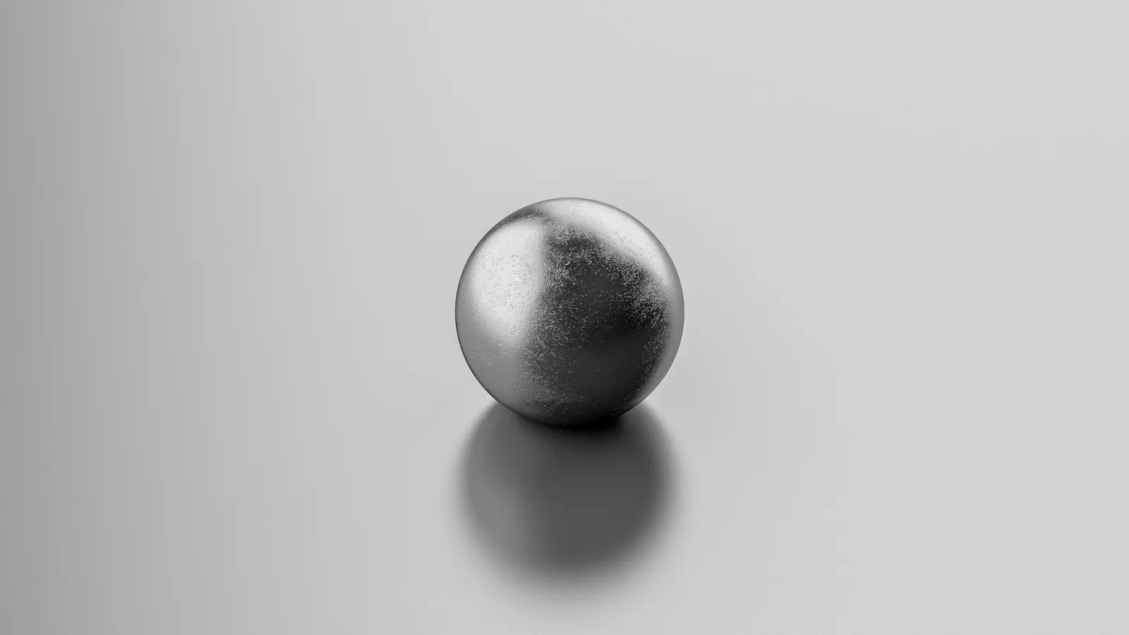 A polished metal sphere on a grey surface