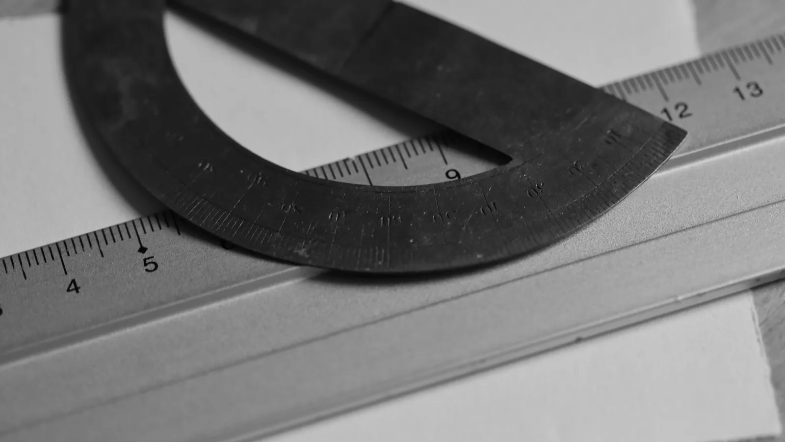 A protractor and ruler lying on white paper