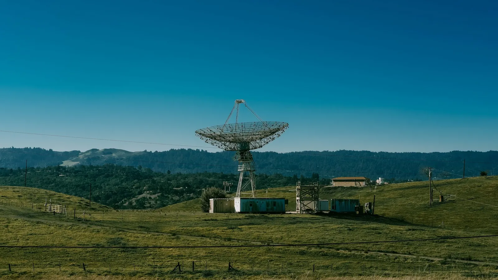 A radio telescope dish standing on open grassland