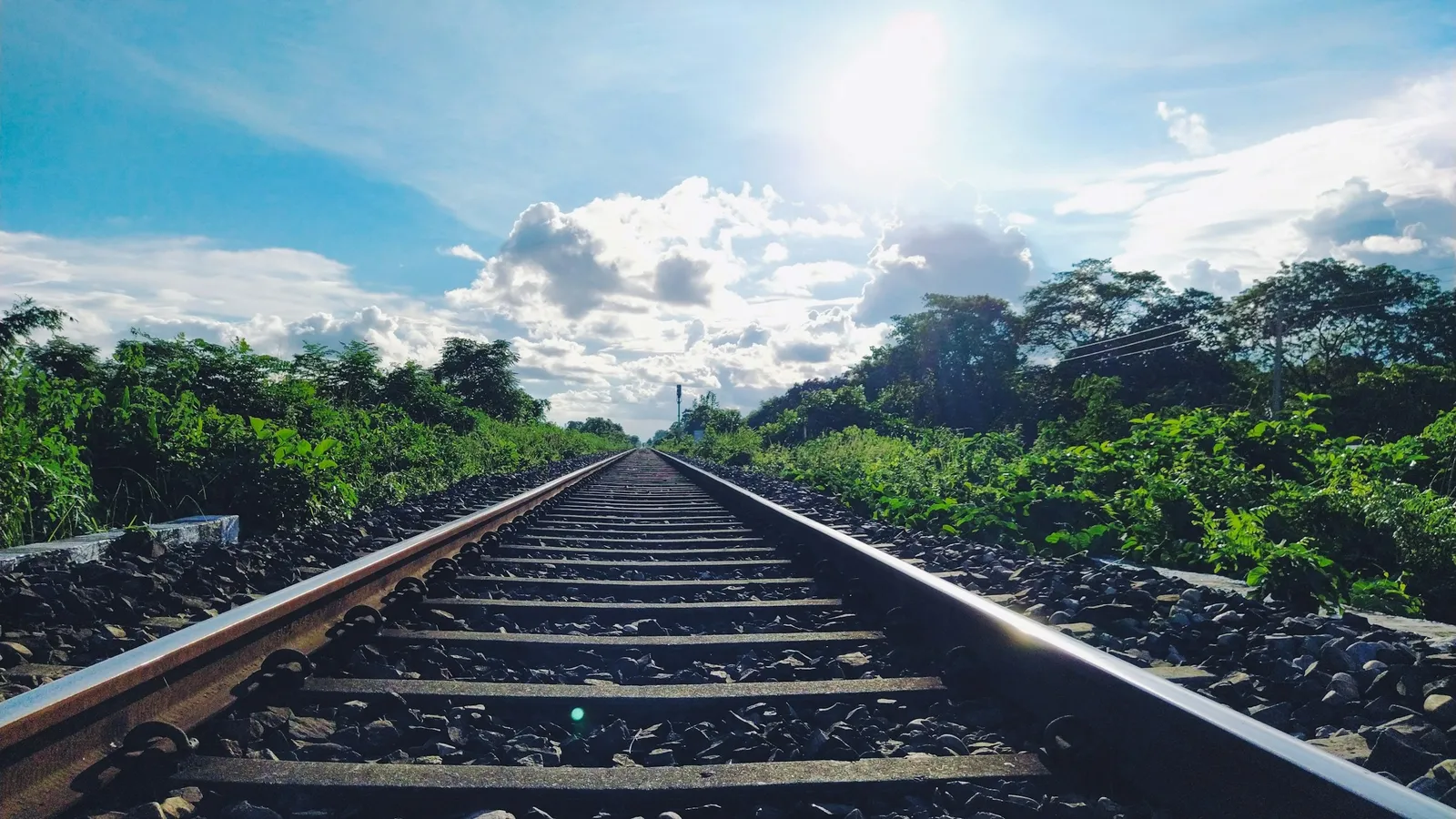 A railway track running straight into the distance under a blue sky